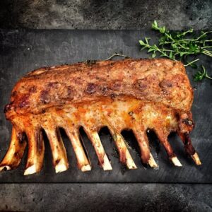Delicious grilled spare ribs served with fresh herbs on a stone surface.