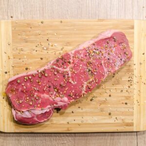 Raw beef steak seasoned with spices on a wooden chopping board. Perfect for cooking enthusiasts.